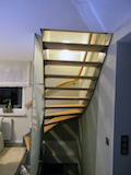 Stahltreppe mit Stufen und Wandhandlauf in Esche-Absturzsicherung mit Glas.